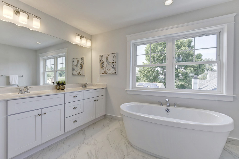 Exempel på ett mellanstort klassiskt vit vitt en-suite badrum, med skåp i shakerstil, vita skåp, ett fristående badkar, en öppen dusch, en toalettstol med hel cisternkåpa, vit kakel, tunnelbanekakel, grå väggar, ljust trägolv, ett undermonterad handfat, marmorbänkskiva, grått golv och med dusch som är öppen