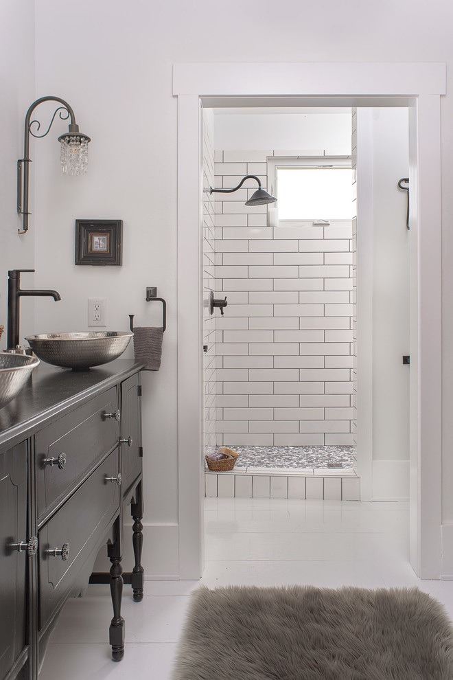 Foto på ett mellanstort lantligt en-suite badrum, med möbel-liknande, grå skåp, en öppen dusch, en vägghängd toalettstol, vit kakel, keramikplattor, vita väggar, målat trägolv, ett fristående handfat, träbänkskiva, vitt golv och med dusch som är öppen