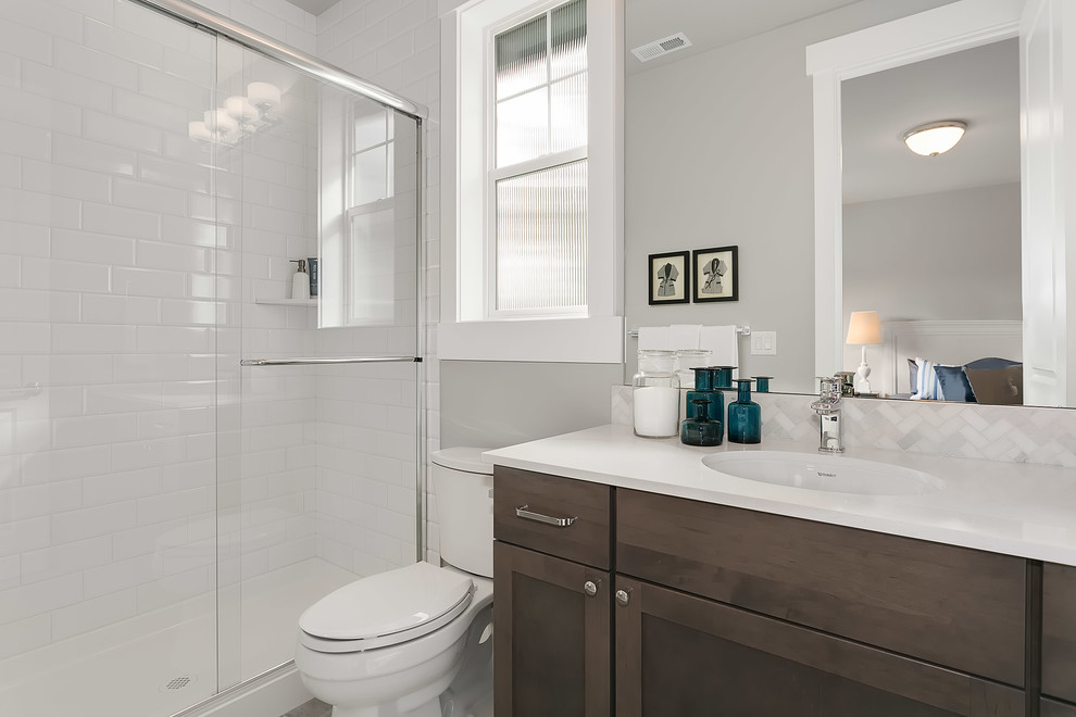 Idéer för ett mellanstort amerikanskt badrum med dusch, med luckor med infälld panel, skåp i mörkt trä, en dusch i en alkov, en toalettstol med separat cisternkåpa, vit kakel, grå väggar, ett undermonterad handfat, bänkskiva i kvarts och dusch med skjutdörr