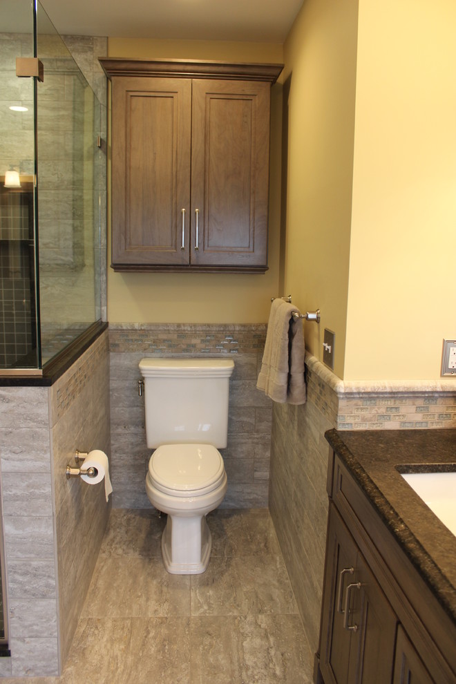 Photo of an expansive traditional ensuite bathroom in Boston with recessed-panel cabinets, grey cabinets, a freestanding bath, a corner shower, a two-piece toilet, grey tiles, porcelain tiles, beige walls, porcelain flooring, a submerged sink and granite worktops.