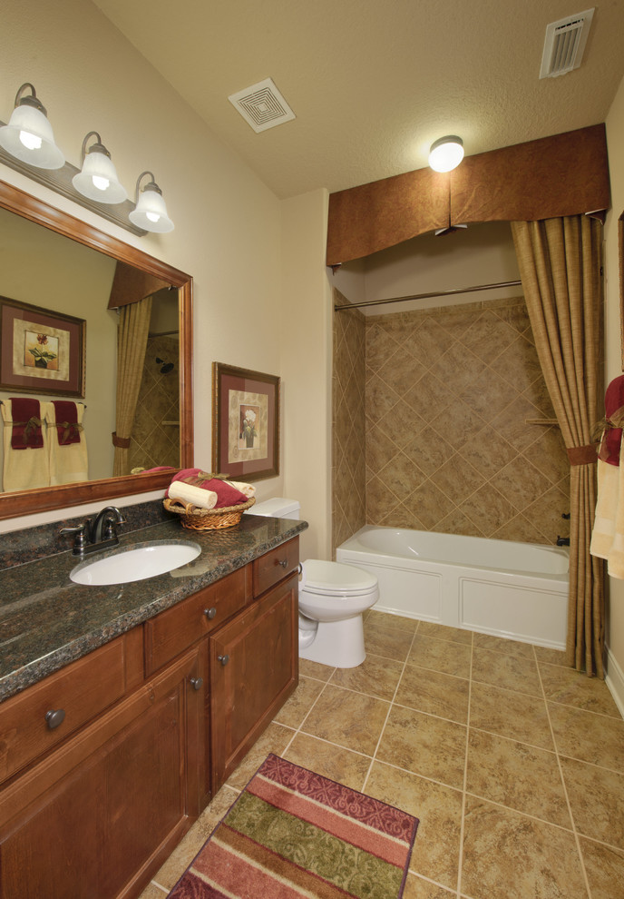Inspiration for a small transitional beige tile and travertine tile travertine floor and beige floor bathroom remodel in Houston with raised-panel cabinets, dark wood cabinets, a two-piece toilet, beige walls, an undermount sink, granite countertops and black countertops