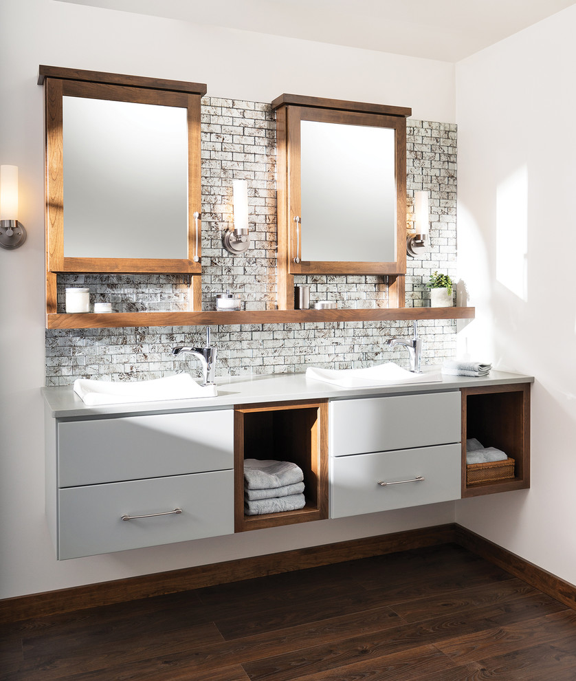 На фото: ванная комната в современном стиле с накладной раковиной, серыми фасадами, столешницей из искусственного камня, серой плиткой, стеклянной плиткой, белыми стенами и темным паркетным полом