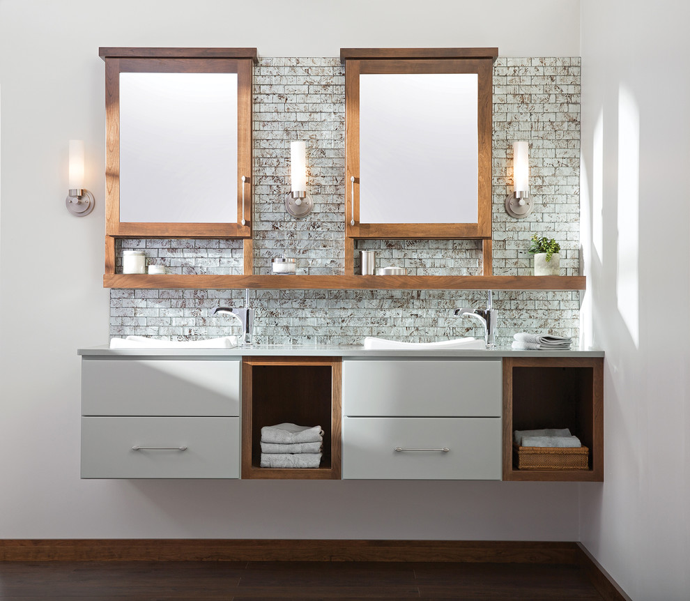 Foto de cuarto de baño contemporáneo con lavabo encastrado, puertas de armario grises, encimera de acrílico, baldosas y/o azulejos grises, baldosas y/o azulejos de vidrio, paredes blancas y suelo de madera oscura