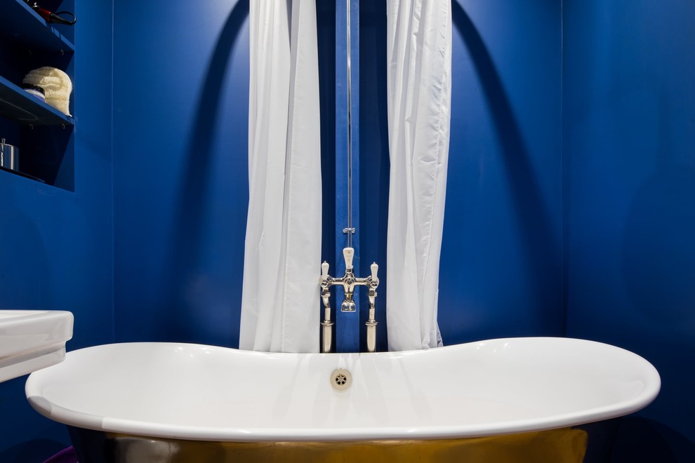 Idéer för att renovera ett mellanstort funkis badrum för barn, med öppna hyllor, blå skåp, ett fristående badkar, en dusch/badkar-kombination, en toalettstol med hel cisternkåpa, blå väggar, mörkt trägolv, ett piedestal handfat, brunt golv och dusch med duschdraperi