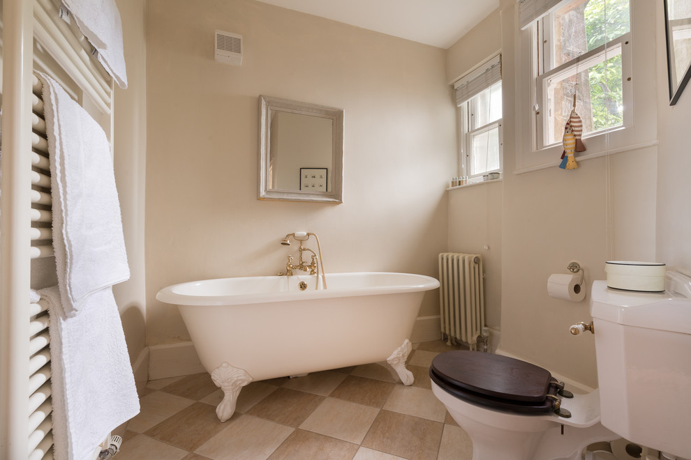 Imagen de cuarto de baño principal campestre de tamaño medio con bañera con patas, sanitario de dos piezas, paredes beige y suelo de baldosas de porcelana