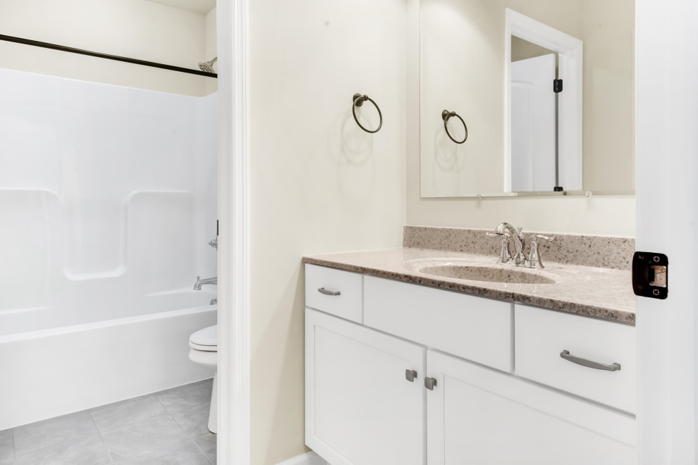 Idéer för att renovera ett mellanstort vintage beige beige badrum för barn, med skåp i shakerstil, vita skåp, ett badkar i en alkov, en dusch/badkar-kombination, en toalettstol med separat cisternkåpa, beige väggar, klinkergolv i keramik, ett integrerad handfat, granitbänkskiva, grått golv och dusch med duschdraperi