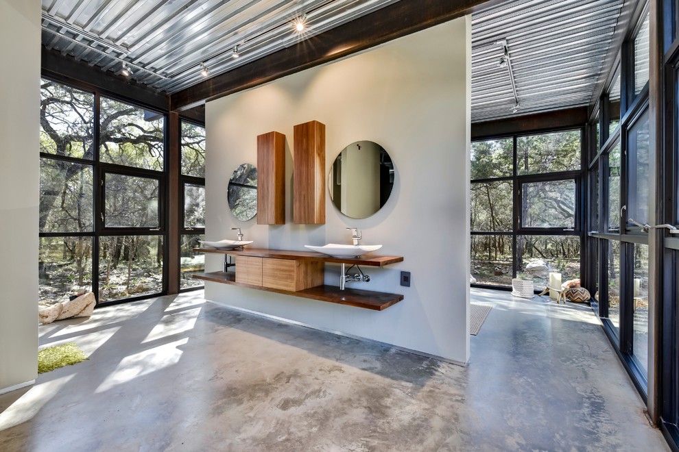 Стильный дизайн: главная ванная комната в стиле лофт с плоскими фасадами, фасадами цвета дерева среднего тона, белыми стенами, бетонным полом, настольной раковиной, столешницей из дерева, серым полом и коричневой столешницей - последний тренд