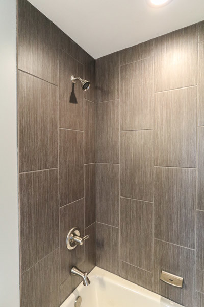 Lantlig inredning av ett litet badrum med dusch, med ett badkar i en alkov, en dusch/badkar-kombination, grå kakel, keramikplattor, blå väggar, klinkergolv i keramik, ett piedestal handfat, grått golv och dusch med duschdraperi