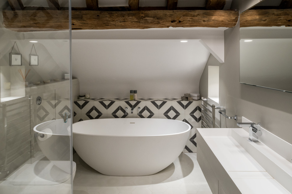 Bild på ett mellanstort lantligt en-suite badrum, med släta luckor, ett fristående badkar, keramikplattor, kalkstensgolv, ett avlångt handfat, bänkskiva i akrylsten och vitt golv