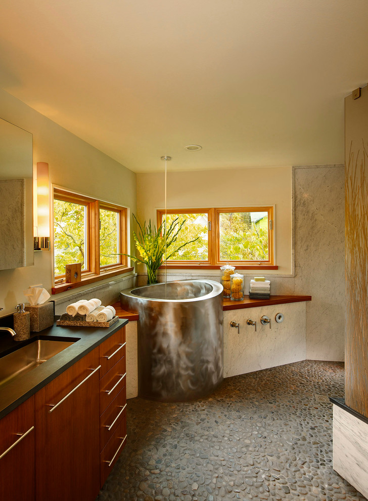 デトロイトにある高級なコンテンポラリースタイルのおしゃれな浴室 (置き型浴槽、木製洗面台、玉石タイル、黒い洗面カウンター) の写真