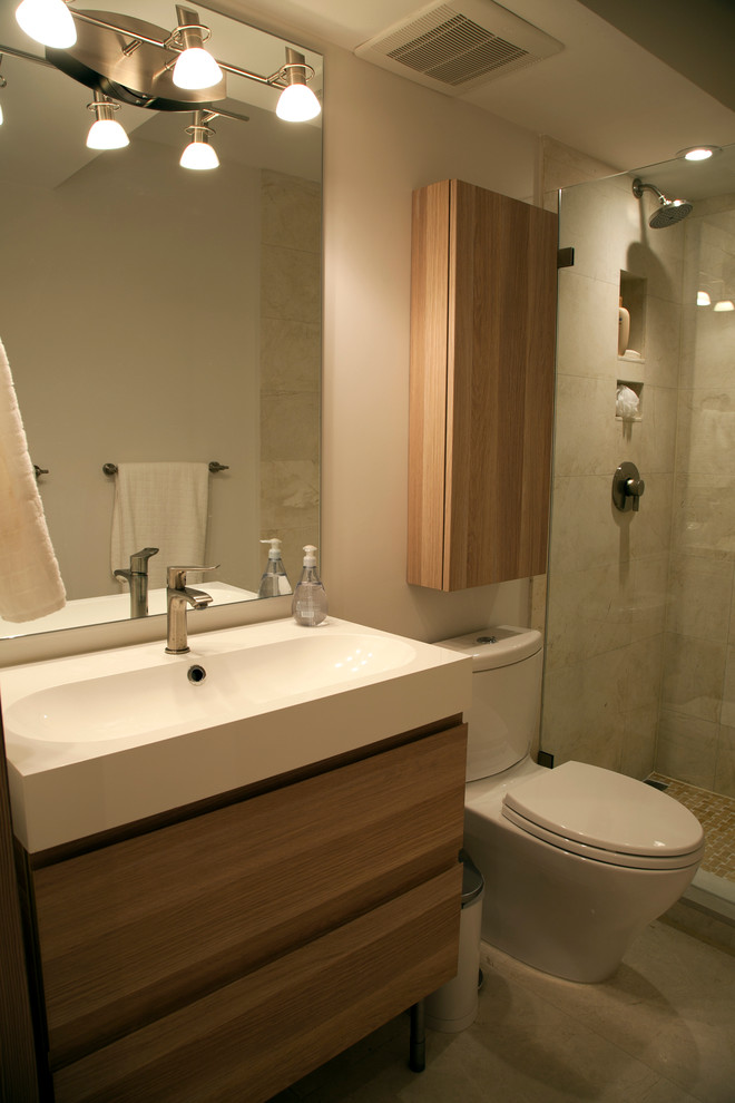 Exemple d'une salle de bain moderne en bois brun de taille moyenne avec un placard à porte plane, WC à poser, un carrelage beige, des carreaux de porcelaine, un mur beige, un sol en calcaire, un lavabo intégré, un sol beige et une cabine de douche à porte battante.