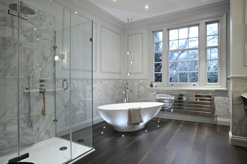ロンドンにあるコンテンポラリースタイルのおしゃれなお風呂の窓 (置き型浴槽、コーナー設置型シャワー、白いタイル、白い壁、濃色無垢フローリング) の写真