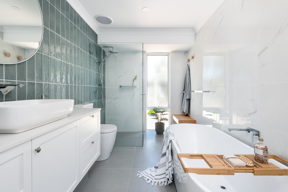 Exempel på ett klassiskt vit vitt badrum, med skåp i shakerstil, vita skåp, ett fristående badkar, grå kakel, vit kakel, vita väggar, ett fristående handfat och grått golv