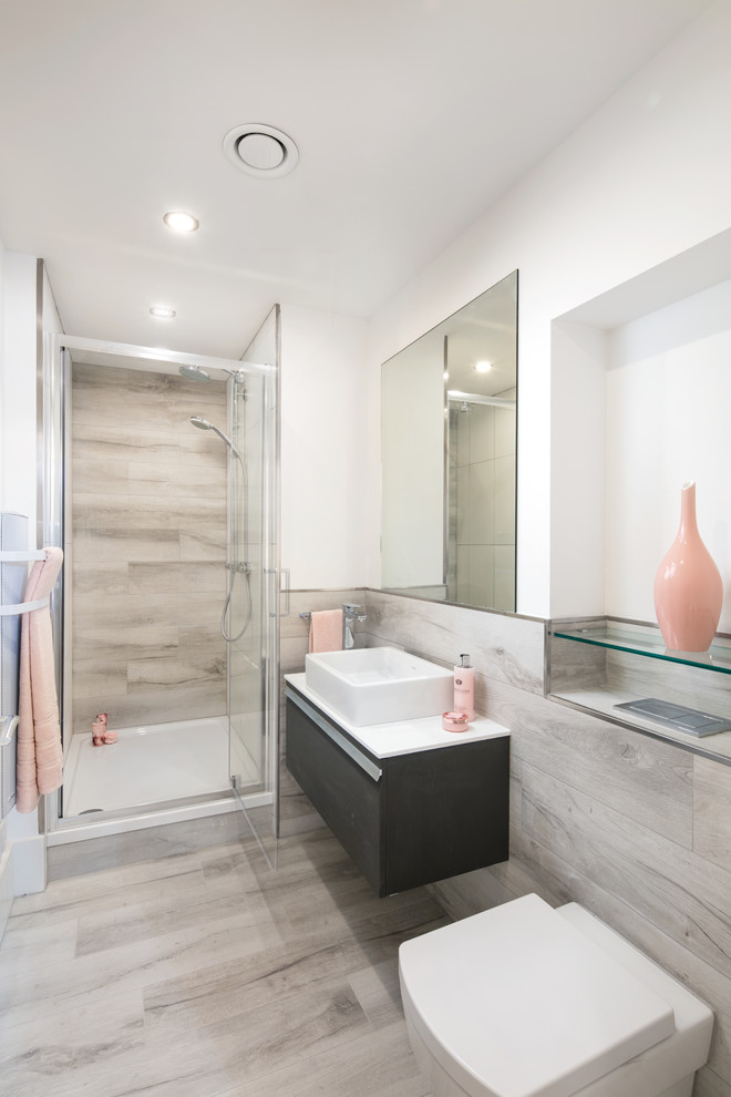 Design ideas for a medium sized contemporary ensuite bathroom in Manchester with freestanding cabinets, dark wood cabinets, an alcove shower, a wall mounted toilet, grey tiles, ceramic tiles, multi-coloured walls, ceramic flooring, a trough sink, laminate worktops, grey floors and a hinged door.