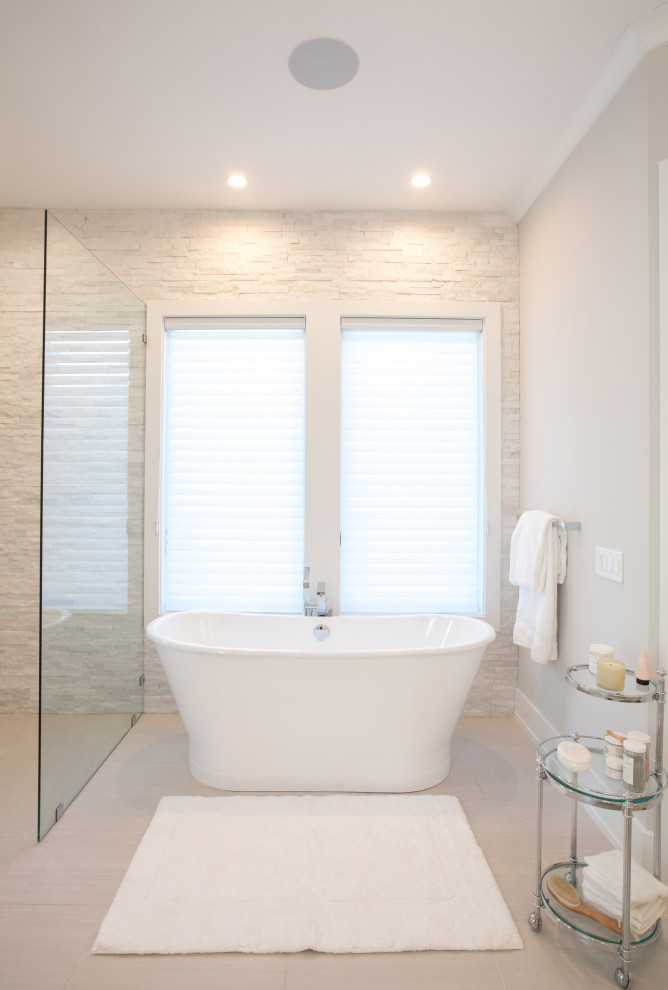 На фото: большая главная ванная комната в стиле неоклассика (современная классика) с отдельно стоящей ванной, серой плиткой, серыми стенами, полом из керамогранита и серым полом