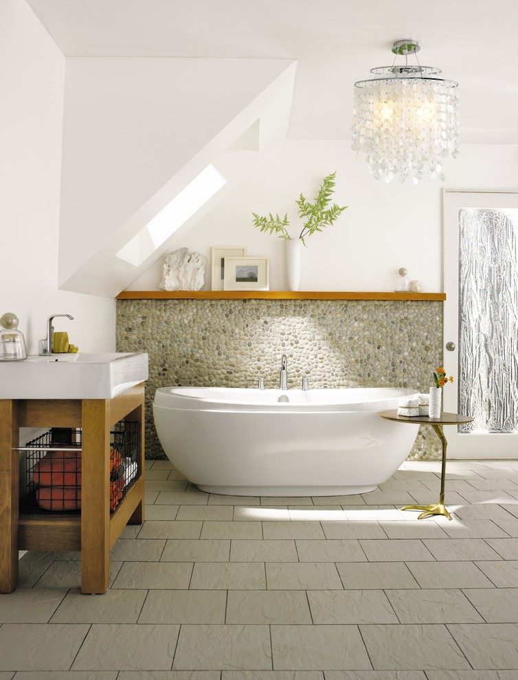 Idée de décoration pour une salle de bain design avec un plan vasque, une baignoire indépendante, une plaque de galets et un mur blanc.