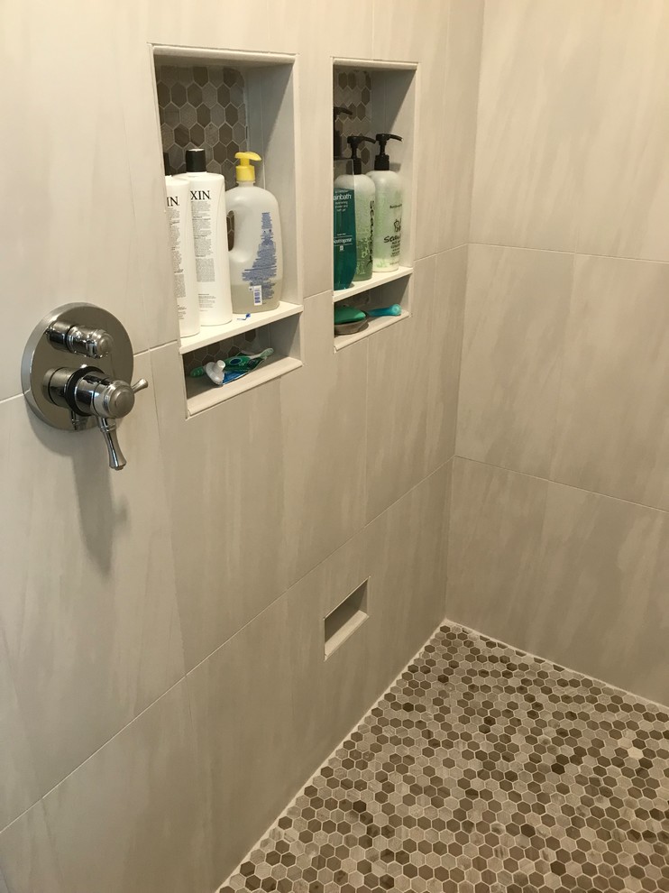 Photo of a medium sized classic ensuite bathroom in Grand Rapids with grey cabinets, a freestanding bath, a built-in shower, grey tiles, glass sheet walls, grey walls, ceramic flooring, a submerged sink, engineered stone worktops, grey floors, an open shower and white worktops.