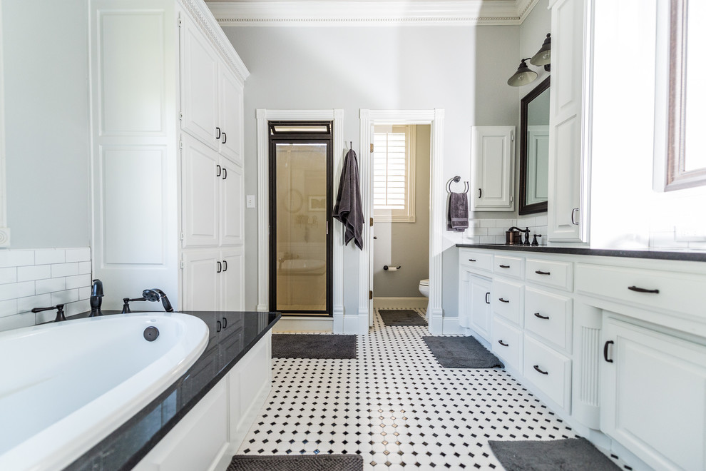Photo of a medium sized rural ensuite bathroom in Dallas with raised-panel cabinets, white cabinets, a built-in bath, black and white tiles, ceramic tiles, grey walls, dark hardwood flooring, a submerged sink and granite worktops.
