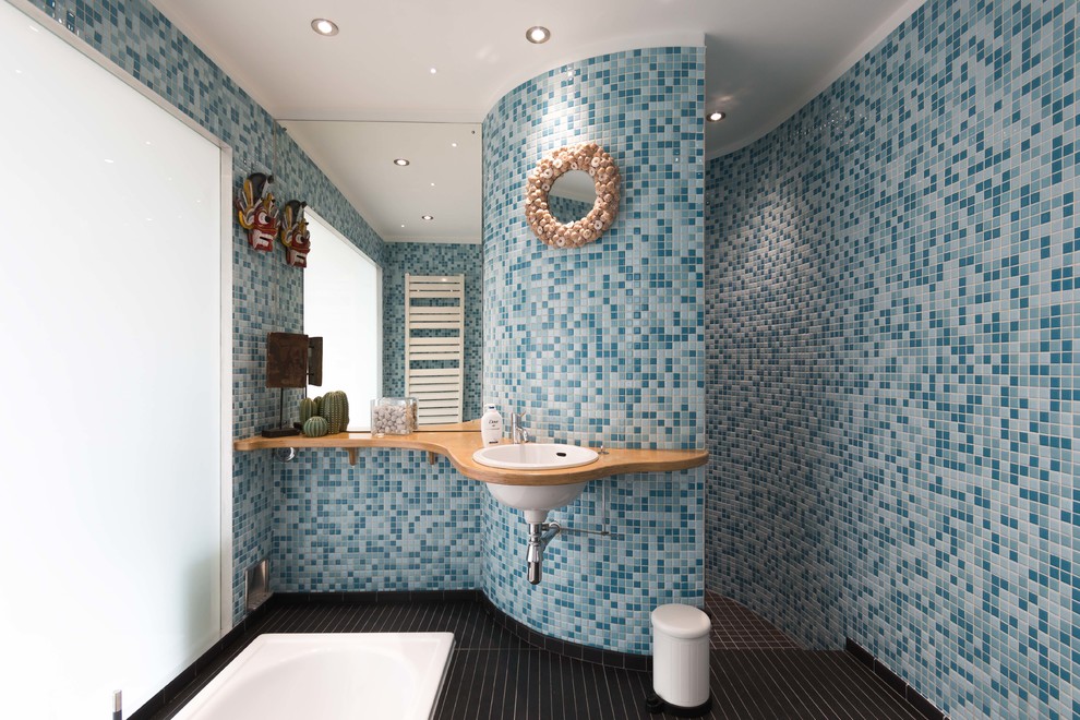 Idée de décoration pour une salle de bain principale design de taille moyenne avec un carrelage bleu, mosaïque, un mur bleu, un sol en carrelage de céramique, un plan de toilette en bois, un sol noir, un plan de toilette beige et un lavabo posé.