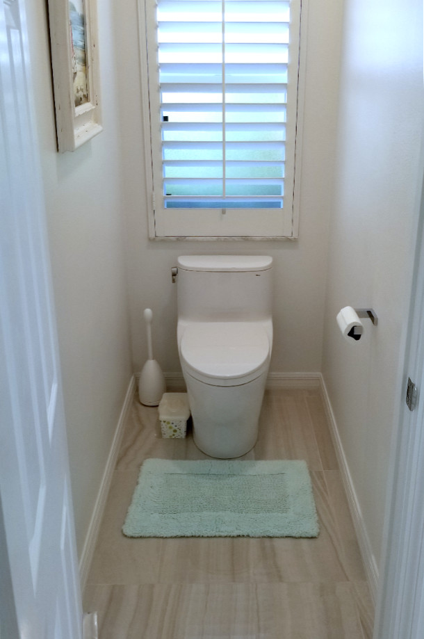 Photo of a small nautical cloakroom in Tampa with a one-piece toilet, white walls and brown floors.