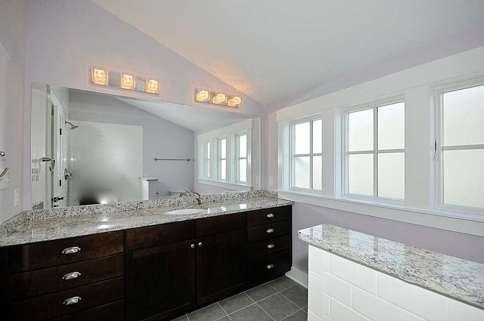 Ejemplo de cuarto de baño de estilo americano con puertas de armario de madera en tonos medios, encimera de granito, baldosas y/o azulejos blancos, paredes púrpuras y suelo de baldosas de cerámica