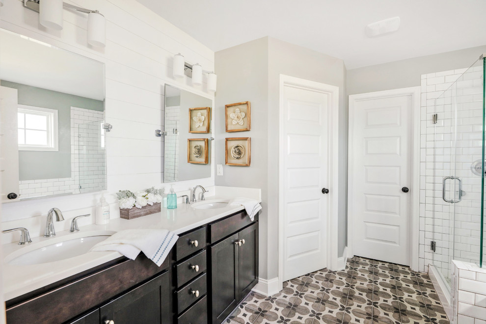 Example of a transitional white tile and subway tile multicolored floor corner shower design in Richmond with shaker cabinets, dark wood cabinets, gray walls, an undermount sink and white countertops