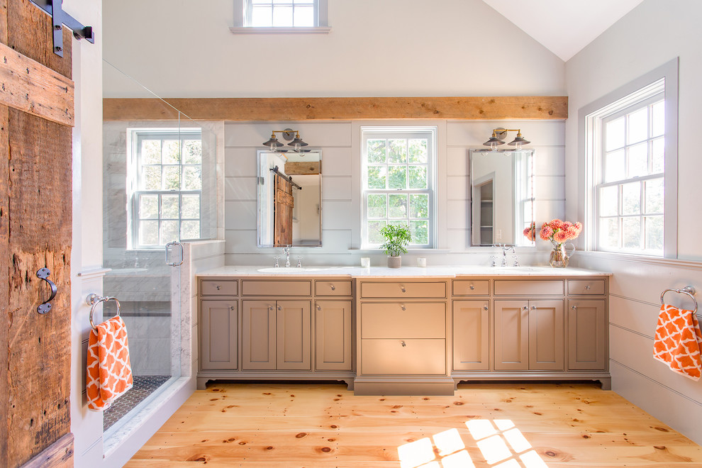 Example of a large farmhouse master white tile and porcelain tile light wood floor doorless shower design in Boston with a drop-in sink, marble countertops, gray walls, brown cabinets and shaker cabinets