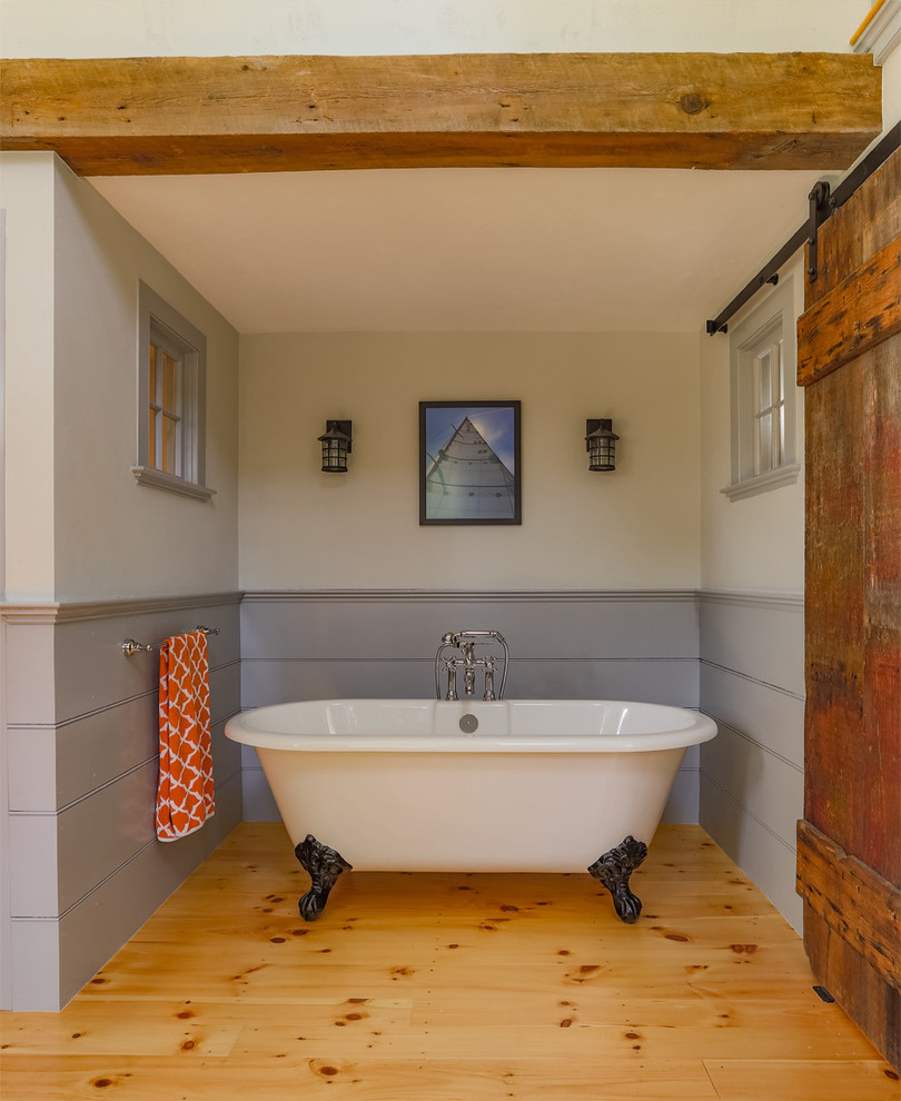 Claw-foot bathtub - country master light wood floor claw-foot bathtub idea in Boston with marble countertops