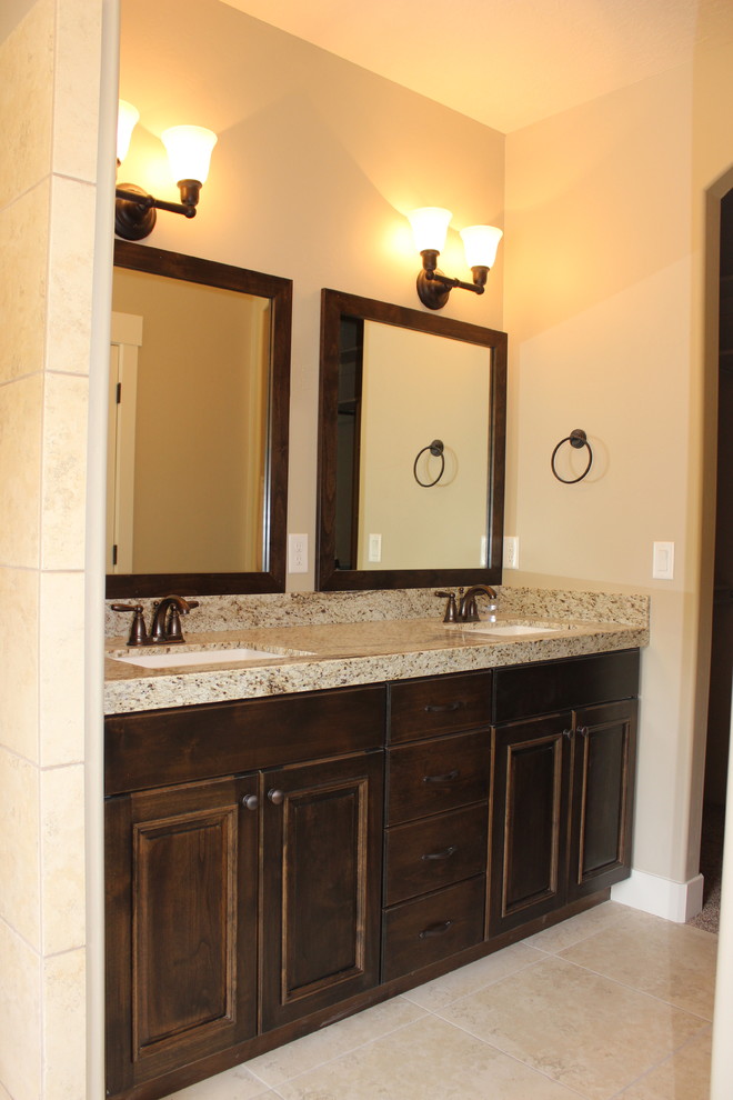 Inspiration for a large traditional ensuite bathroom in Salt Lake City with a submerged sink, raised-panel cabinets, dark wood cabinets, granite worktops, a corner bath, a walk-in shower, a two-piece toilet, beige tiles, ceramic tiles, beige walls and ceramic flooring.