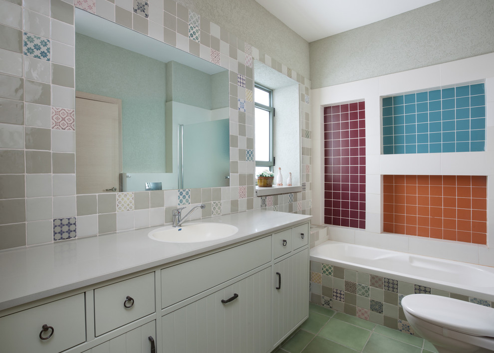 Imagen de cuarto de baño actual con puertas de armario blancas, baldosas y/o azulejos multicolor, suelo verde y encimeras grises