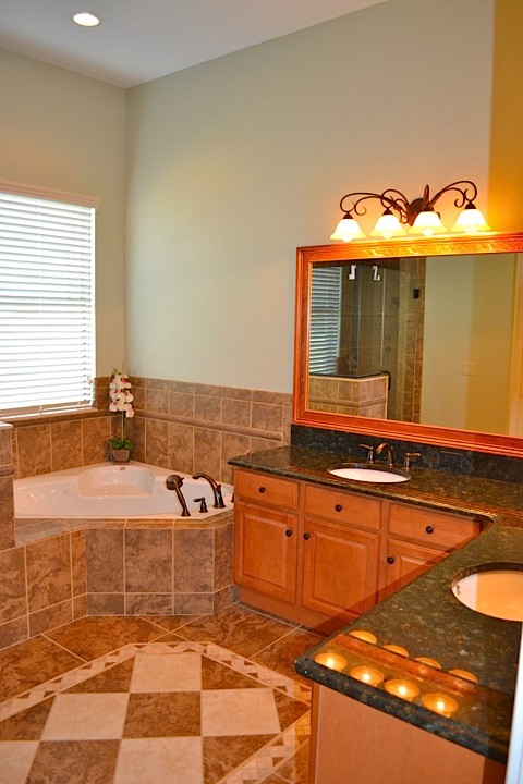 Réalisation d'une salle de bain principale tradition en bois brun de taille moyenne avec un placard avec porte à panneau surélevé, une baignoire d'angle, un plan de toilette en granite, une douche d'angle, un lavabo encastré, un mur vert et un sol en carrelage de céramique.