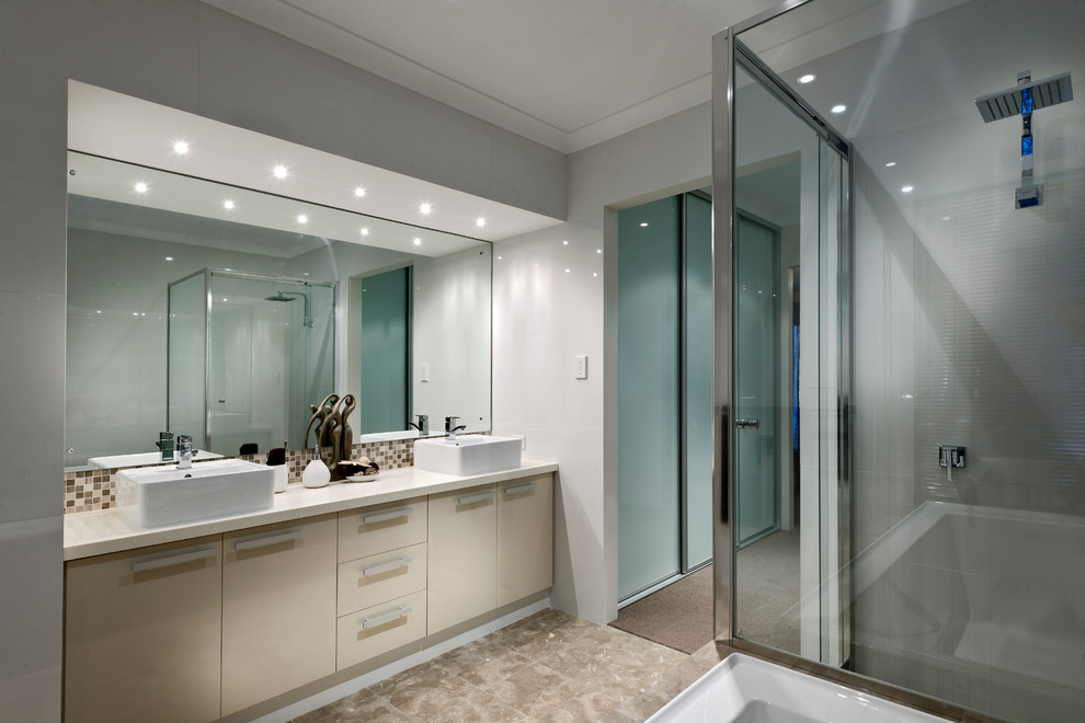 На фото: главная ванная комната в стиле модернизм с накладной раковиной, плоскими фасадами, бежевыми фасадами, столешницей из гранита, угловым душем, разноцветной плиткой, керамической плиткой, серыми стенами и полом из керамической плитки с