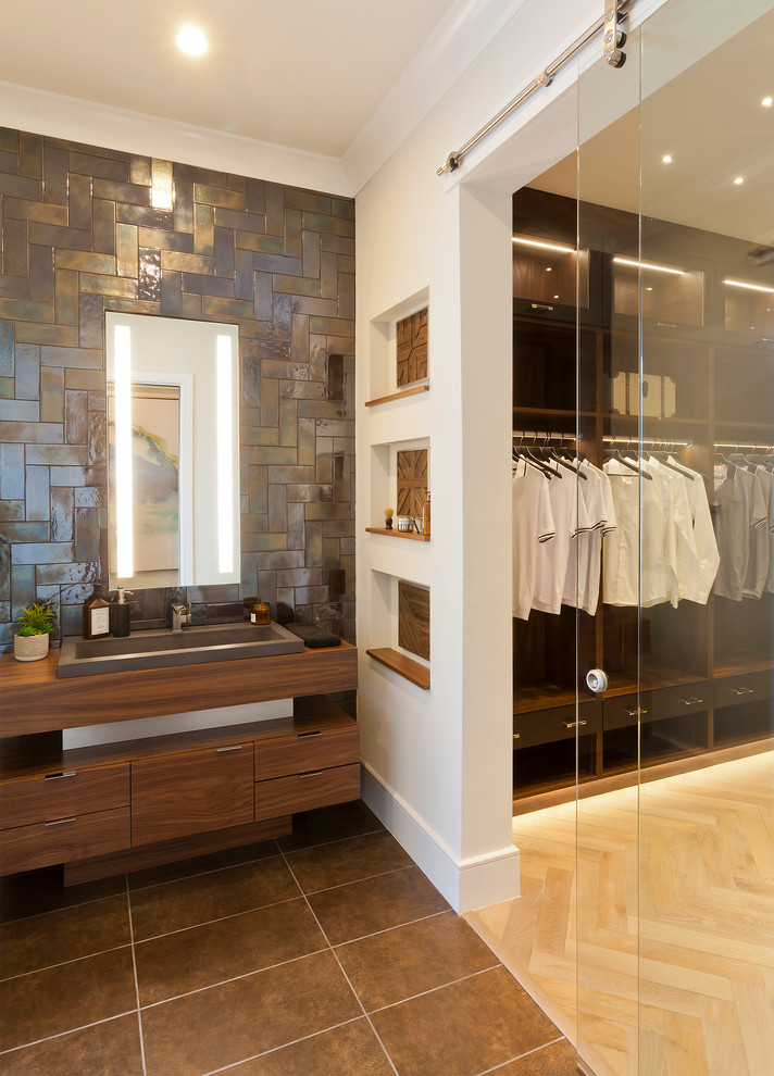 This is an example of an expansive traditional ensuite bathroom in Tampa with flat-panel cabinets, medium wood cabinets, a corner shower, a one-piece toilet, brown tiles, metro tiles, white walls, porcelain flooring, a built-in sink, wooden worktops, brown floors, a hinged door and brown worktops.