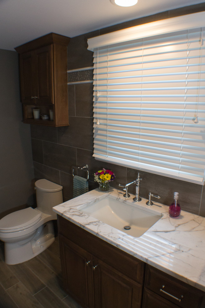 Idéer för ett mellanstort klassiskt badrum med dusch, med luckor med upphöjd panel, skåp i mellenmörkt trä, en öppen dusch, en toalettstol med hel cisternkåpa, grå kakel, porslinskakel, grå väggar, klinkergolv i porslin, ett undermonterad handfat och marmorbänkskiva