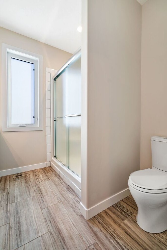 This is an example of a medium sized classic ensuite bathroom in Other with shaker cabinets, dark wood cabinets, an alcove shower, a two-piece toilet, beige tiles, ceramic tiles, beige walls, ceramic flooring, a submerged sink, quartz worktops, beige floors and a sliding door.