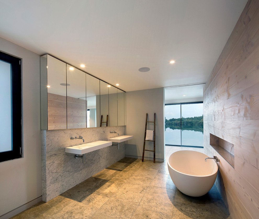 Idee per una stanza da bagno contemporanea di medie dimensioni con lavabo sospeso, vasca freestanding, piastrelle beige, pareti grigie e lastra di pietra