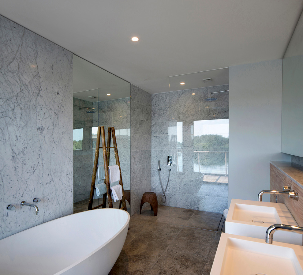 Réalisation d'une salle de bain design de taille moyenne pour enfant avec un lavabo suspendu, une baignoire indépendante, une douche à l'italienne, un carrelage beige, un mur gris et des dalles de pierre.