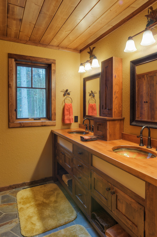 他の地域にあるラスティックスタイルのおしゃれな浴室 (アンダーカウンター洗面器、シェーカースタイル扉のキャビネット、濃色木目調キャビネット、木製洗面台、黄色い壁) の写真
