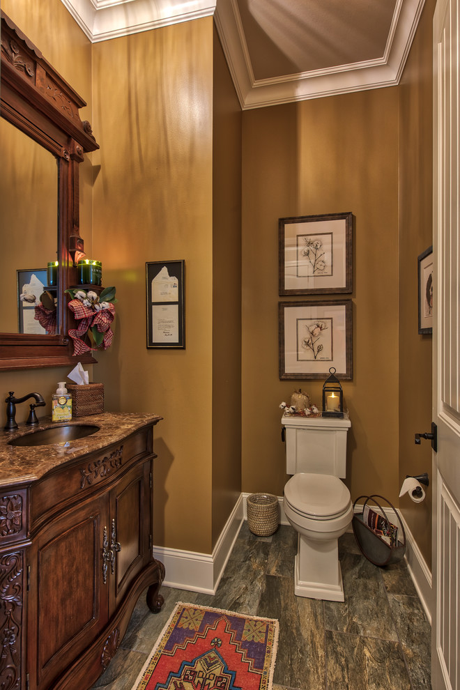 Bild på ett litet vintage toalett, med luckor med upphöjd panel, grå skåp, en toalettstol med separat cisternkåpa, brun kakel, porslinskakel, grå väggar, klinkergolv i porslin, ett undermonterad handfat, marmorbänkskiva och grått golv