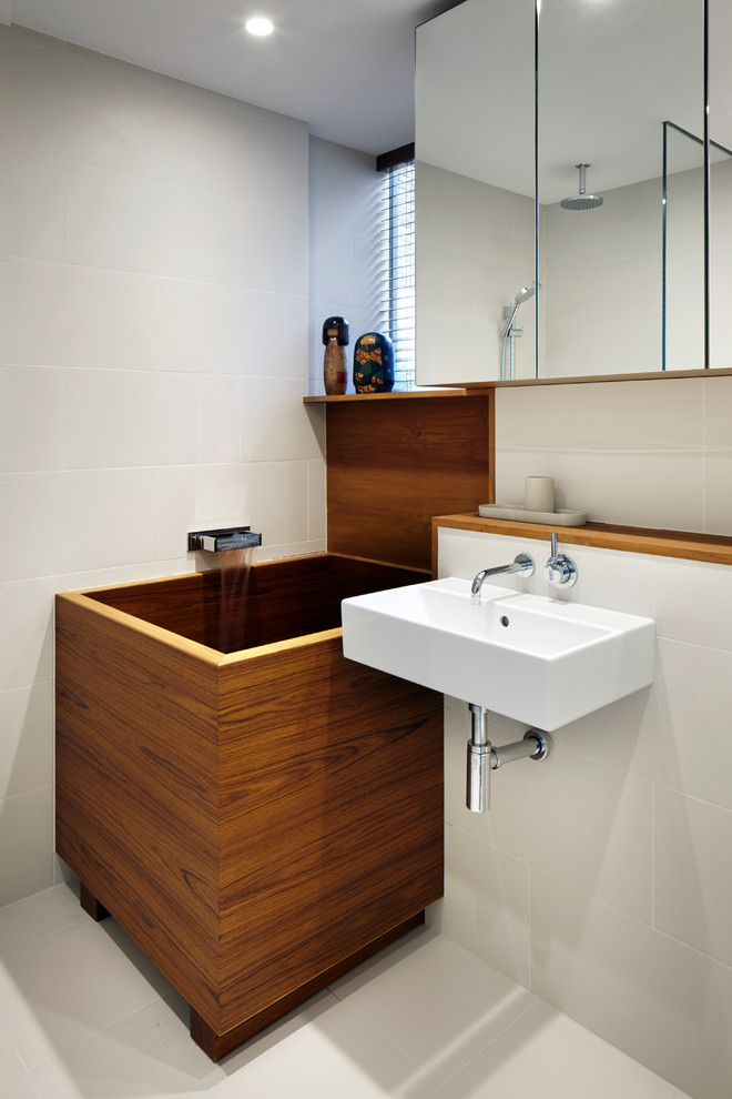На фото: ванная комната в восточном стиле с подвесной раковиной, японской ванной и бежевой плиткой