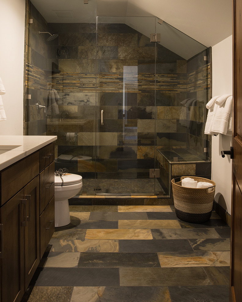 Bild på ett stort rustikt badrum med dusch, med skåp i shakerstil, skåp i mörkt trä, brun kakel, bruna väggar, ett undermonterad handfat, en dusch i en alkov, en toalettstol med separat cisternkåpa, skifferkakel, skiffergolv, marmorbänkskiva, flerfärgat golv och dusch med gångjärnsdörr