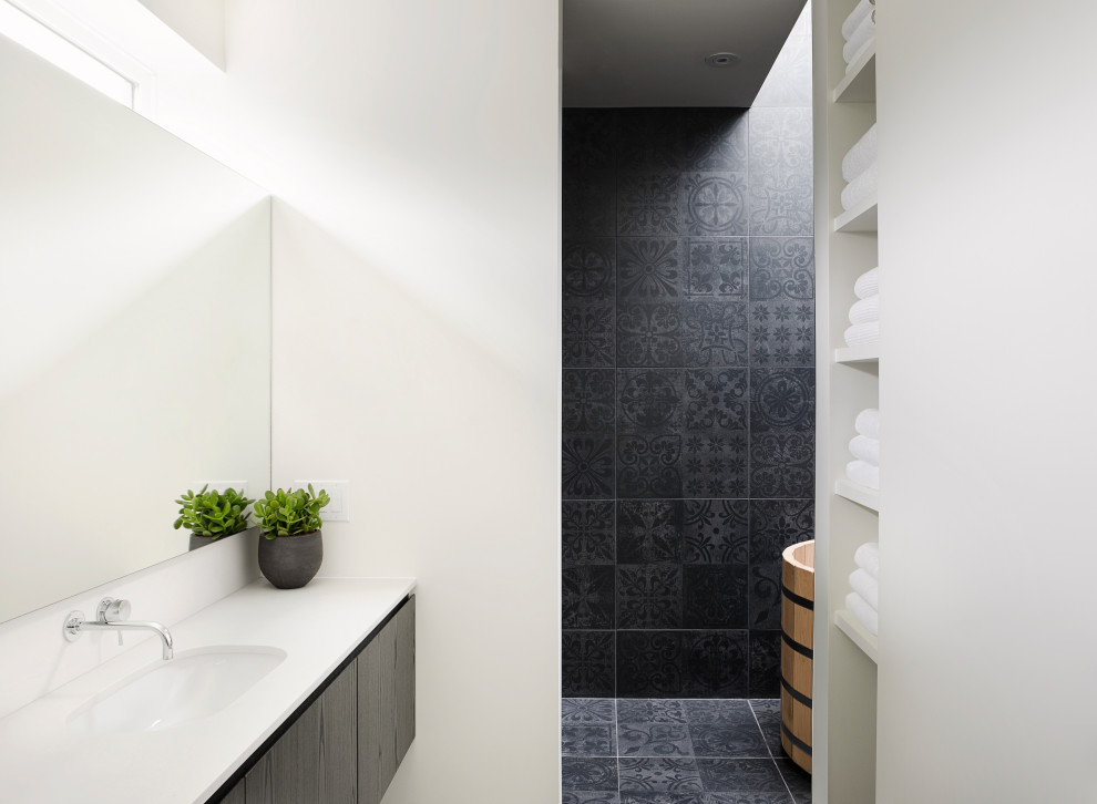 Inspiration for a medium sized contemporary ensuite bathroom in Calgary with flat-panel cabinets, dark wood cabinets, a japanese bath, a built-in shower, a wall mounted toilet, black tiles, porcelain tiles, white walls, a submerged sink, engineered stone worktops, an open shower, white worktops and black floors.