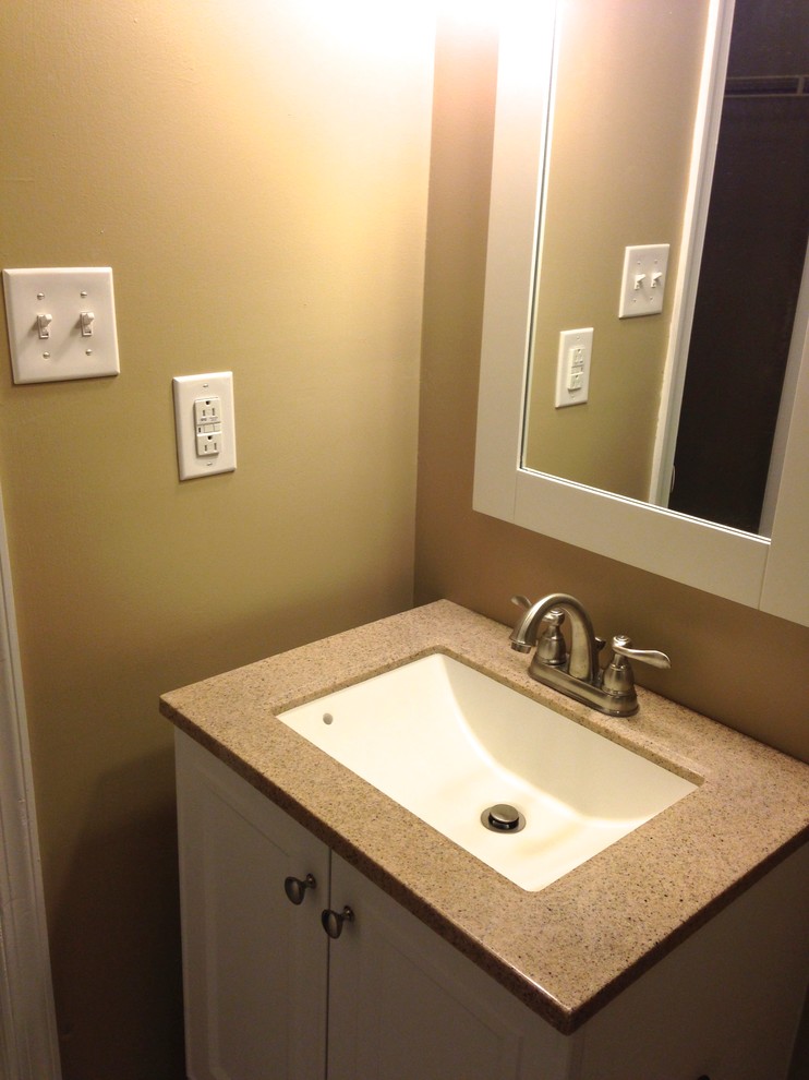 Idéer för att renovera ett litet vintage en-suite badrum, med ett integrerad handfat, släta luckor, vita skåp, bänkskiva i akrylsten, ett badkar i en alkov, en dusch/badkar-kombination, en toalettstol med hel cisternkåpa, vit kakel, porslinskakel, beige väggar och klinkergolv i porslin