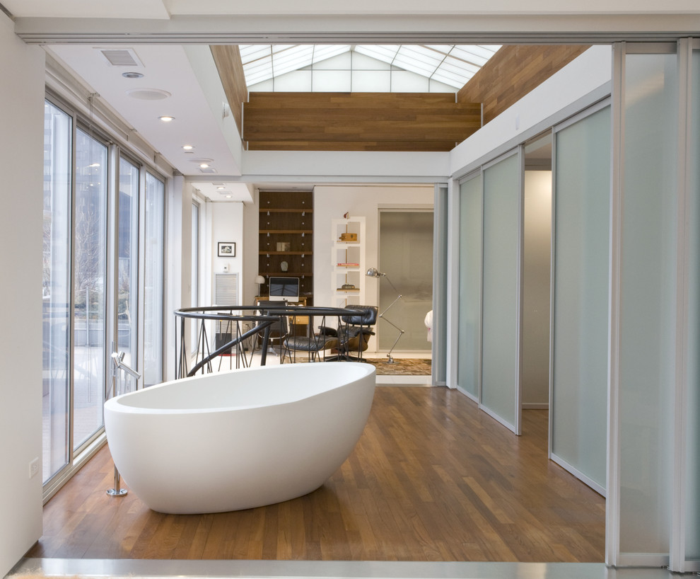 Foto de cuarto de baño principal contemporáneo grande con bañera exenta, suelo de madera en tonos medios y suelo marrón