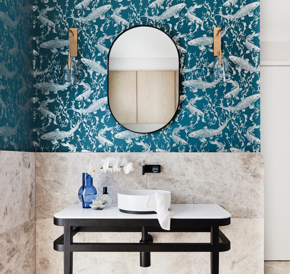 Aménagement d'une salle de bain contemporaine avec des portes de placard noires, un carrelage beige, un mur bleu, une vasque, un sol beige, un plan de toilette blanc, meuble simple vasque, meuble-lavabo sur pied et du papier peint.