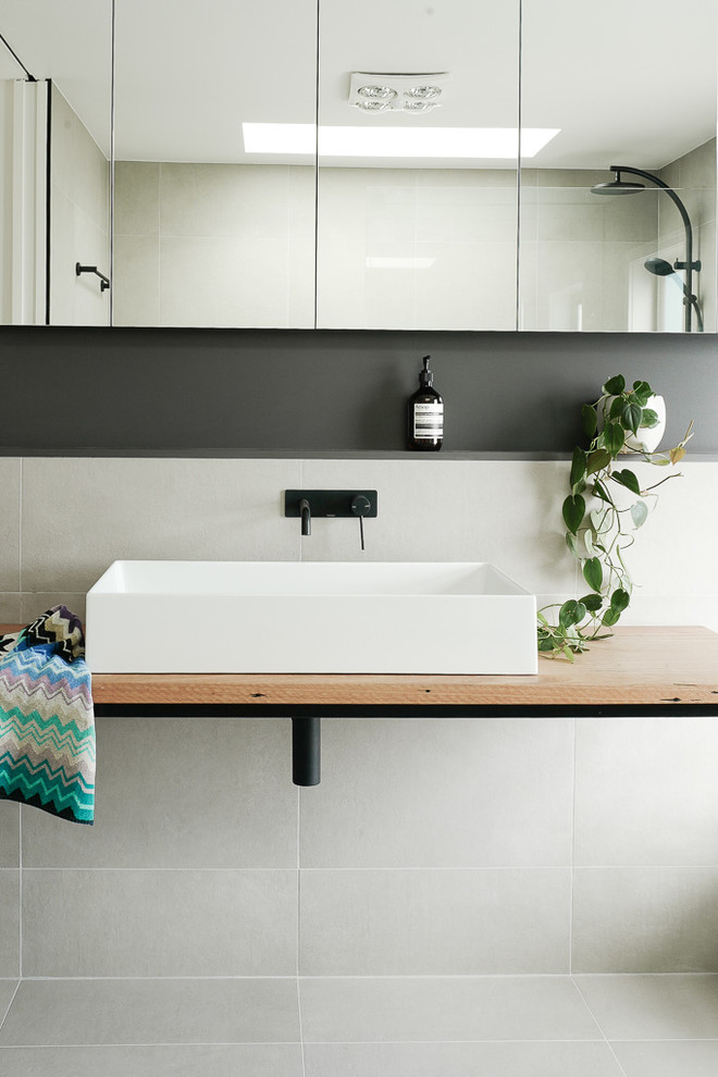 Diseño de cuarto de baño contemporáneo con baldosas y/o azulejos blancos, paredes blancas, lavabo sobreencimera, encimera de madera, suelo blanco y encimeras marrones