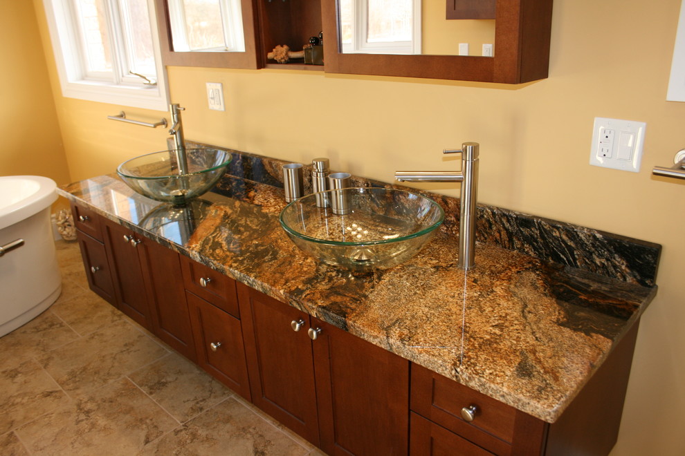 Elegant beige tile and porcelain tile bathroom photo in Toronto with a vessel sink, shaker cabinets, medium tone wood cabinets, granite countertops and a two-piece toilet