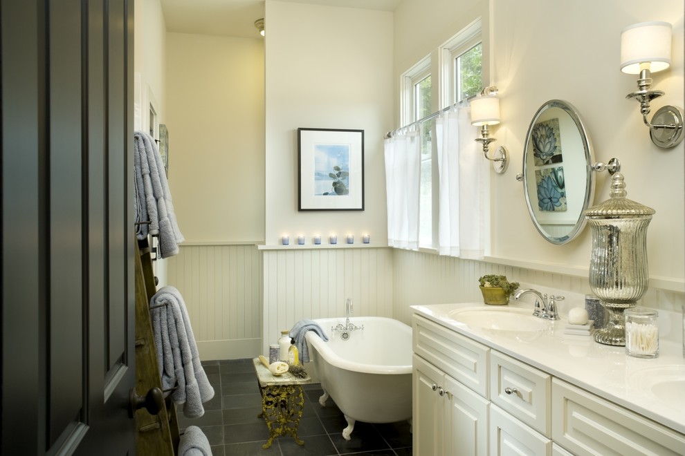 Cette image montre une salle de bain principale traditionnelle avec un lavabo encastré, un placard avec porte à panneau surélevé, des portes de placard blanches, une baignoire sur pieds, un mur blanc et une fenêtre.