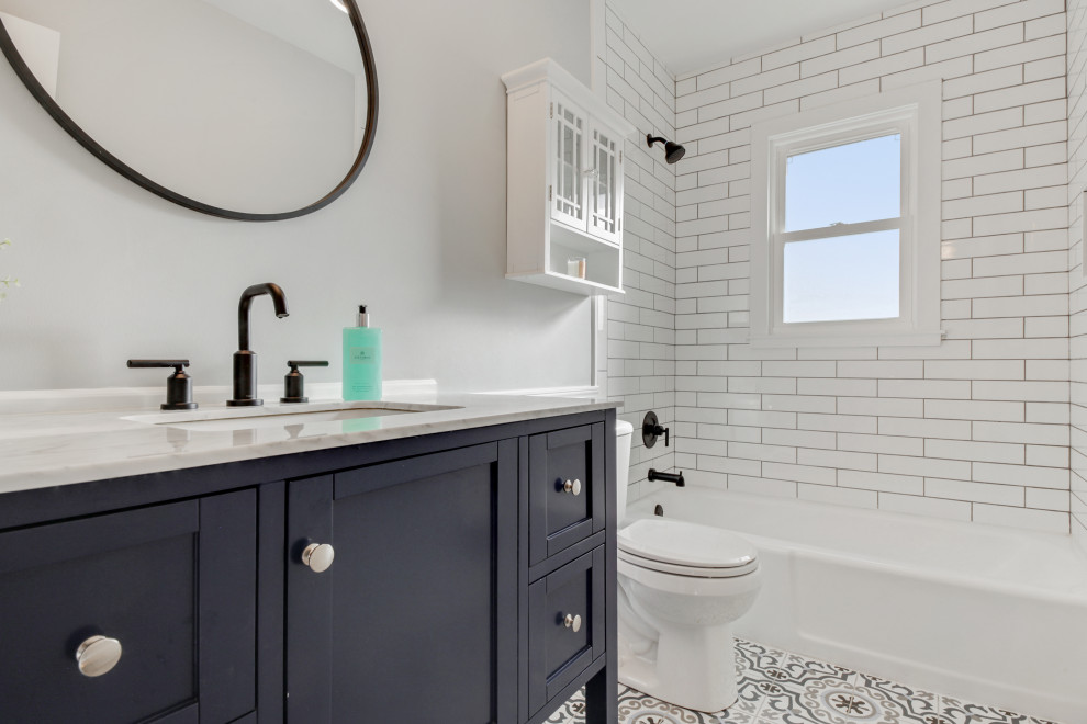Foto på ett mellanstort lantligt badrum, med luckor med infälld panel, blå skåp, vit kakel, mosaikgolv och bänkskiva i kvartsit