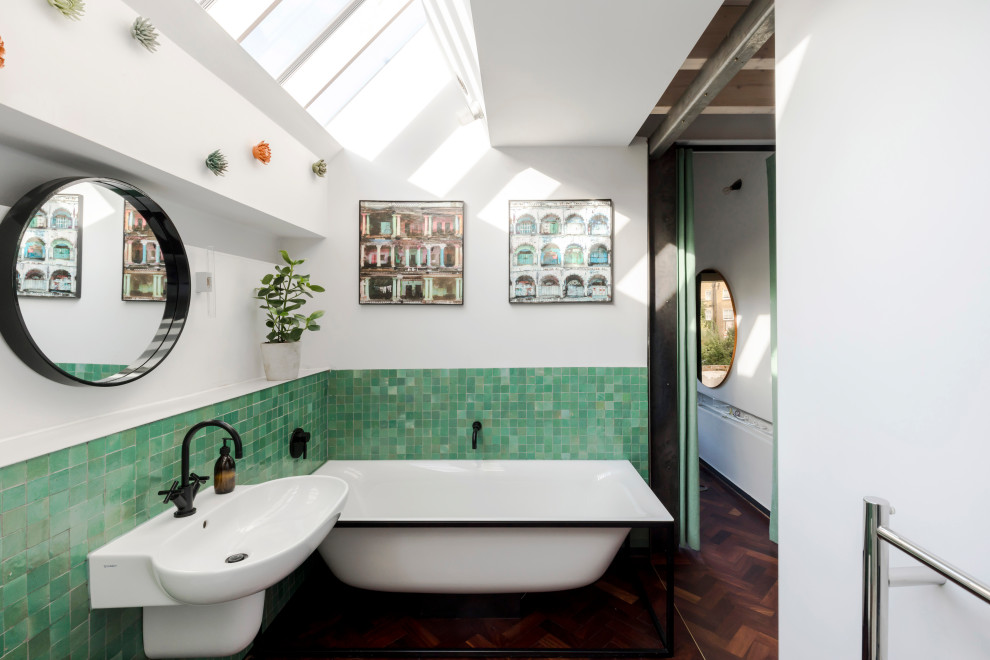 Ejemplo de cuarto de baño único actual con bañera con patas, baldosas y/o azulejos verdes, paredes blancas, suelo de madera oscura, lavabo suspendido y suelo marrón